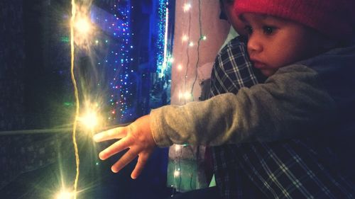 Side view of young man holding illuminated light at night