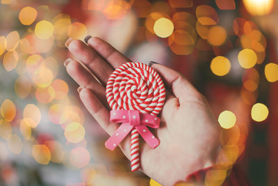 Close-up of hand holding candy against illuminated light