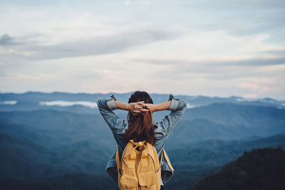 Rear view of woman standing on mountain against sky