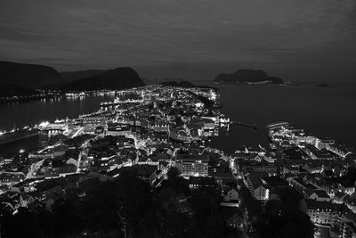 High angle view of illuminated city by sea against sky