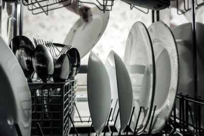 Close-up of cutlery and plates on rack