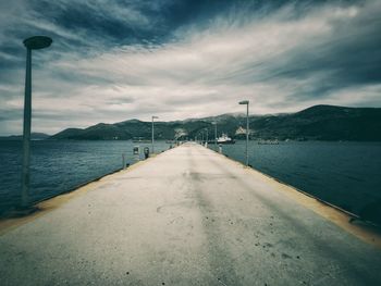 Empty road by sea against sky