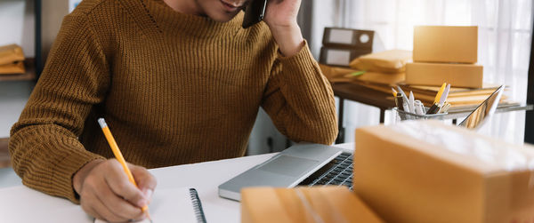 Midsection of woman using mobile phone while sitting on table