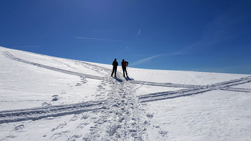 People hiking on snow covered mountain against sky