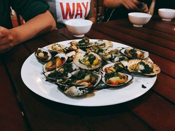 Midsection of people by scallops in plate at restaurant