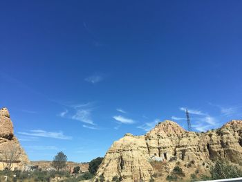 Low angle view of rocky mountain against blue sky