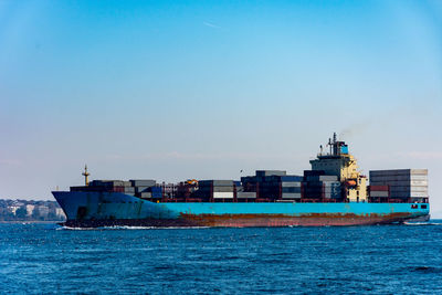 Container ship in sea against blue sky