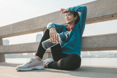 Full length of young woman sitting on wall