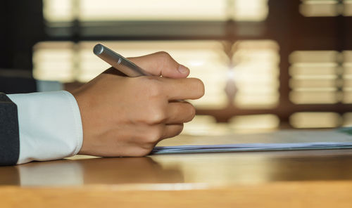 Midsection of man holding smart phone on table