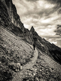 Man walking on cliff against sky