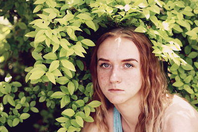 Close-up portrait of young woman by plants