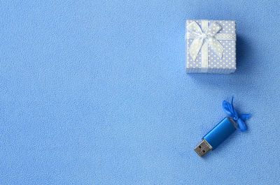 High angle view of usb stick and gift against blue background
