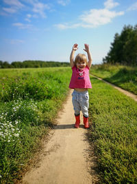 Full length of girl standing on field against sky