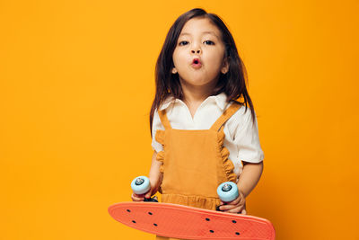 Portrait of young woman holding book against yellow background