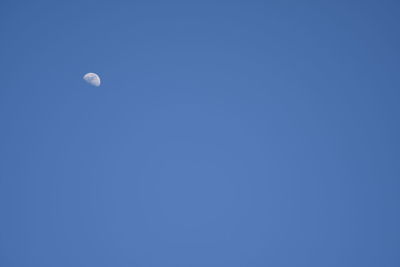 Low angle view of moon against blue sky