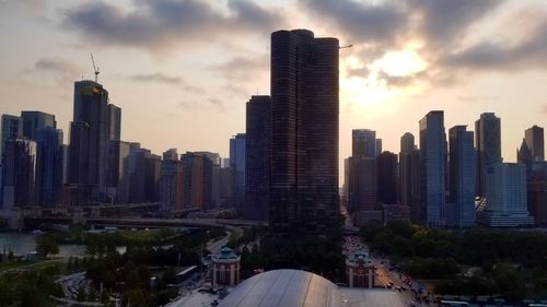 Modern buildings in city against sky during sunset