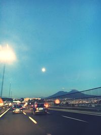 Illuminated road against blue sky at night