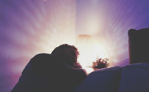 Low angle view of silhouette woman on sofa at night