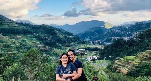 Portrait of smiling couple standing mountains against sky