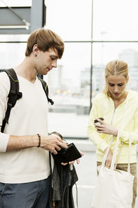 Man and woman searching something in wallet and bag at railroad station