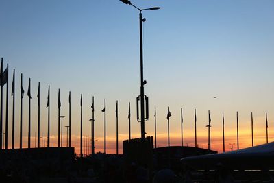 Silhouette street lights against orange sky