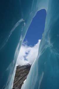 Low angle view of snowcapped mountain against blue sky