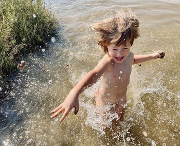 High angle view of shirtless boy playing in river