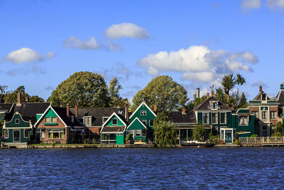 Houses by river and buildings against sky