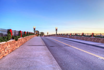 Empty road against blue sky during sunset