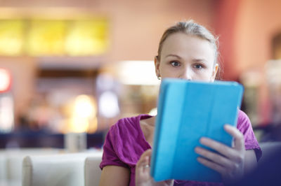 Close-up of young woman with digital tablet sitting in airport