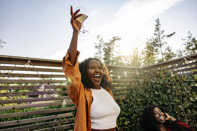 Excited young woman screaming while celebrating during dinner party