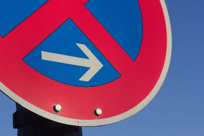 Close-up of road sign against blue sky