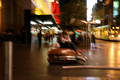 Blurred motion of people on street in city at night