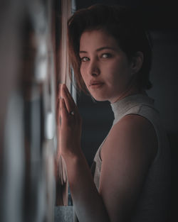 Portrait of young woman looking through window