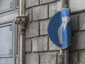 Low angle view of road sign by wall