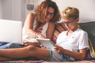 Young woman using mobile phone while sitting on laptop