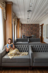 Woman sitting on sofa and reading at home