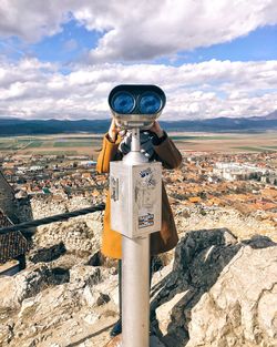 Woman looking through coin-operated binoculars on cliff