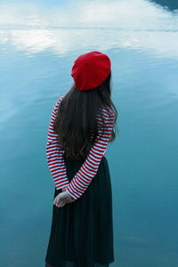 Rear view of woman standing by sea against sky