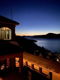 Silhouette building by sea against clear sky during sunset