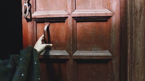 Close-up of a historic wooden door and a female hand