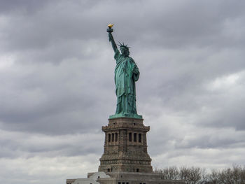 Low angle view of statue of liberty against cloudy sky