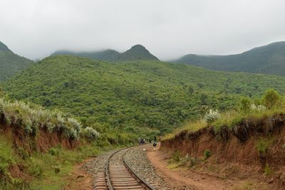 Scenic view of railroad track by mountains against sky