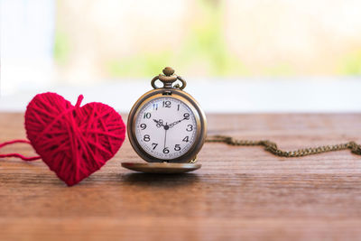 Close-up of pocket watch and heart shape on table