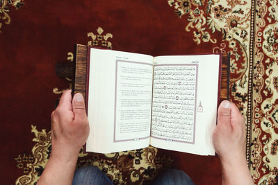 Midsection of man reading koran in mosque