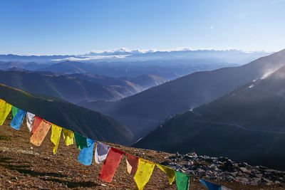 Prayer flags hanging against mountains and blue sky on sunny day