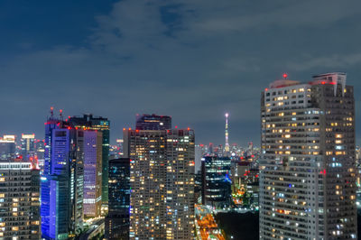 Illuminated buildings in city against sky at night