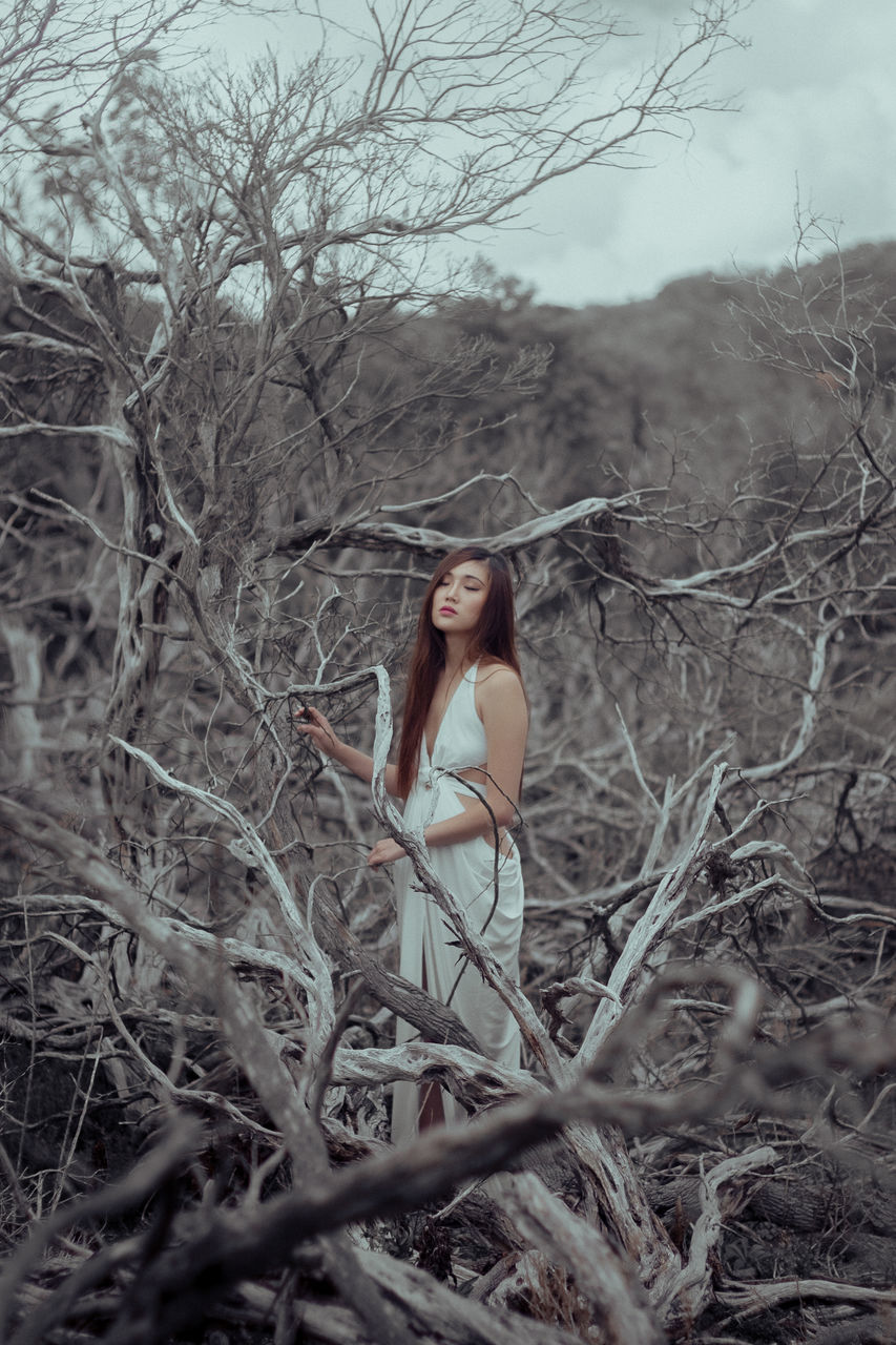 one person, beautiful woman, bare tree, beauty, tree, nature, portrait, long hair, standing, one woman only, looking at camera, women, outdoors, young adult, branch, day, beautiful people, adult, only women, full length, fashion model, young women, one young woman only, adults only, beauty in nature, sky, people