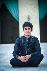 Portrait of young man sitting on floor 