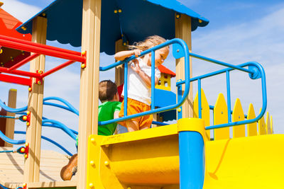 Low angle view of girl standing on slide in playground